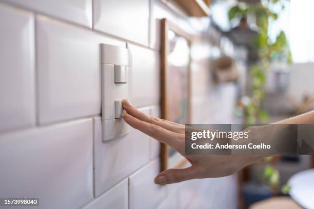 caucasian woman turning on light by switch - turning on or off stock pictures, royalty-free photos & images