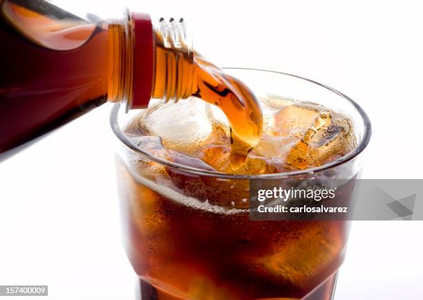 soda (cola) being poured into plain glass with ice - frisdrank stockfoto's en -beelden