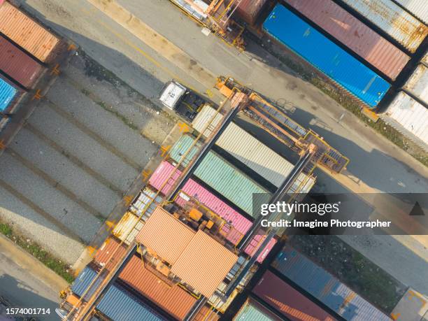 aerial top view, crane is working to unload containers from container transporter truck in a warehouse. business logistic, import, export background image. - transporter stock pictures, royalty-free photos & images