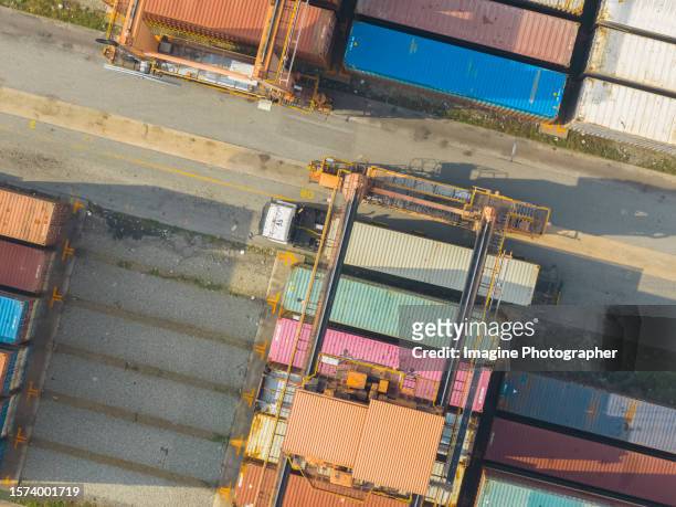 aerial top view, crane is working to unload containers from container transporter truck in a warehouse. business logistic, import, export background image. - transporter stock pictures, royalty-free photos & images