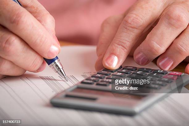 mature woman auditing data printout with calculator - subtraction stock pictures, royalty-free photos & images