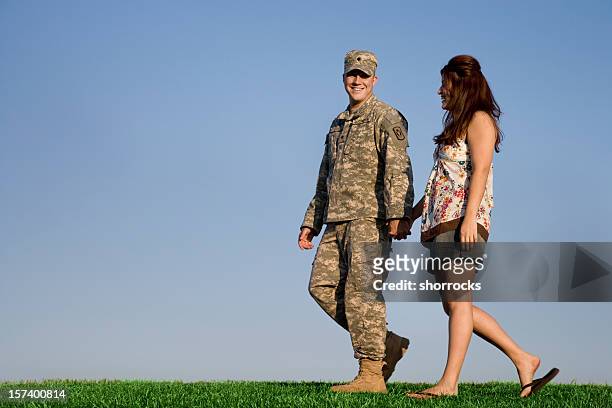 military couple walks hand in hand on clear sunny day - military spouse stock pictures, royalty-free photos & images