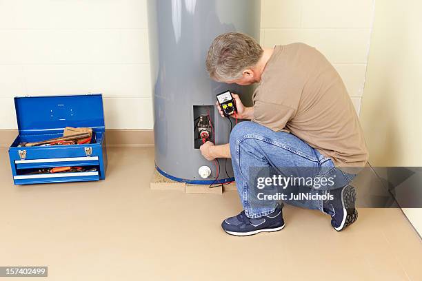 a plumber working in a water heater - boiler stockfoto's en -beelden