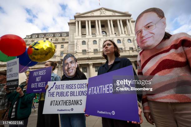 Demonstrators wearing masks depicting Andrew Bailey, governor of the Bank of England, right, and Rishi Sunak, UK prime minister, centre, protest...