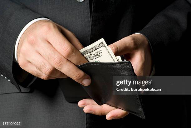 businessman removing american bill from black leather wallet - greed stock pictures, royalty-free photos & images