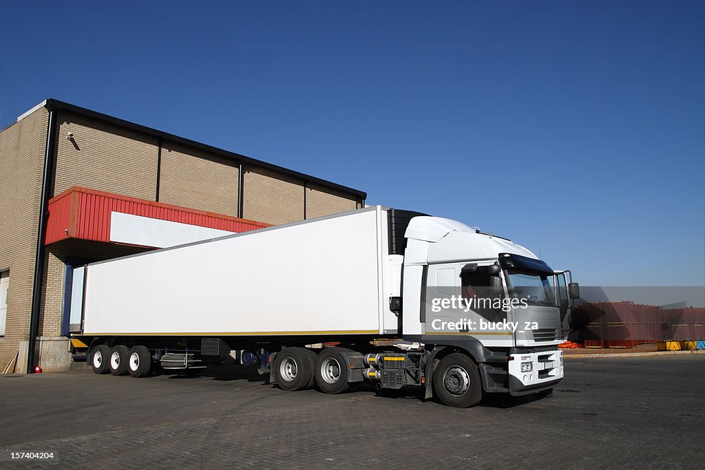 Refrigerated semi truck at a cold storage warehouse loading bay.