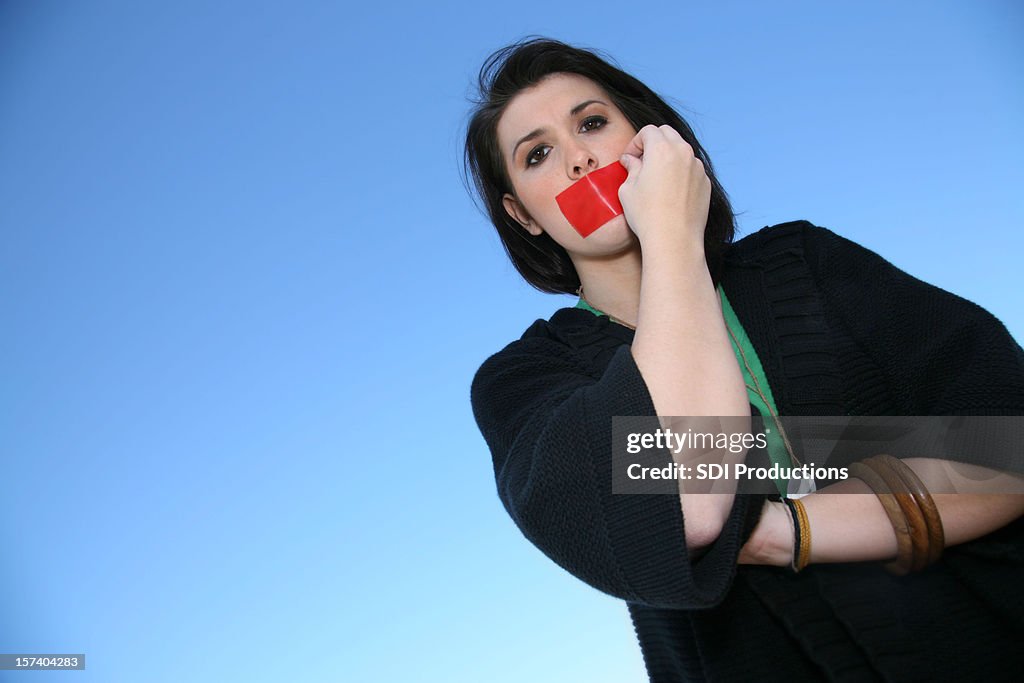 Woman pulling tape off her mouth