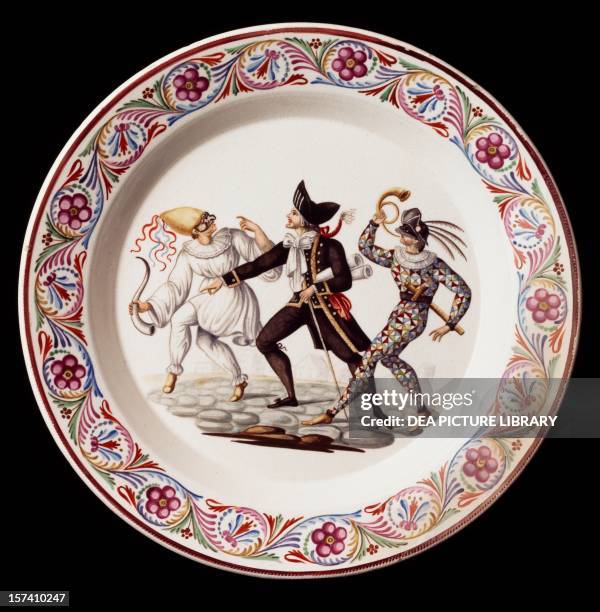 Plate decorated with a scene from Commedia dell'Arte, with masks of Pulcinella, Arlecchino and Balanzone, maiolica, Giustiniani manufacture, Naples....