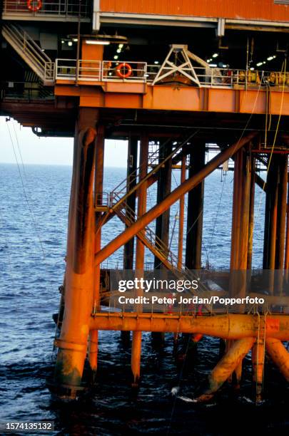 View from a helicopter of maintenance workers on the legs of the Tartan Alpha oil rig installation, owned by the Texaco oil company, above the Tartan...