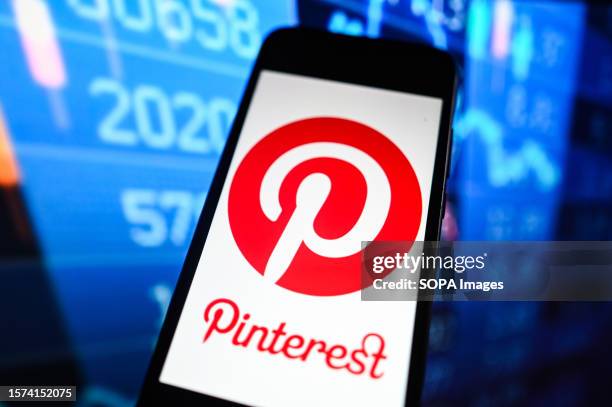 In this photo illustration a Pinterest logo is seen displayed on a smartphone with stock market percentages on the background.