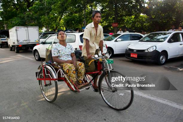 Rickshaw passes by at large car auction lot November 29, 2012 Yangon, Myanmar. Import restrictions have been eased, resulting in many new cars seen...