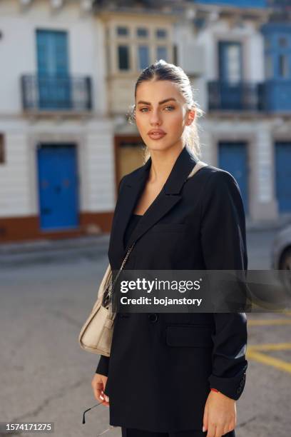 attractive young woman in black suit walking in the city - malta business stock pictures, royalty-free photos & images
