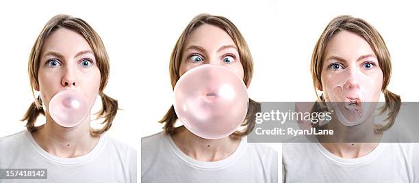 girl blowing bubble gum which pops on her face - bubble gum stockfoto's en -beelden