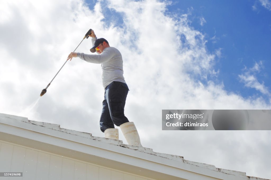 Day laborer pressure cleaning a roof