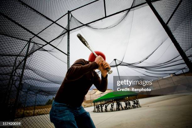 baseball practice: man at batting cages - slagkooi stockfoto's en -beelden