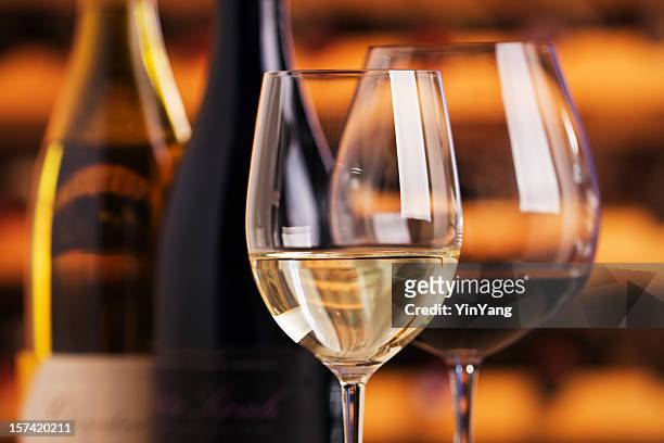 rot- und weißwein in flaschen, gläser mit weinkeller hintergrund - red and white wine glasses stock-fotos und bilder