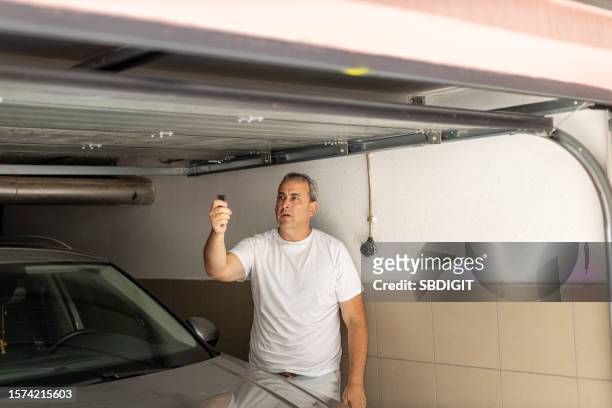 mann, der garagentor schließt, nachdem er sein auto geparkt hat - garagentor stock-fotos und bilder