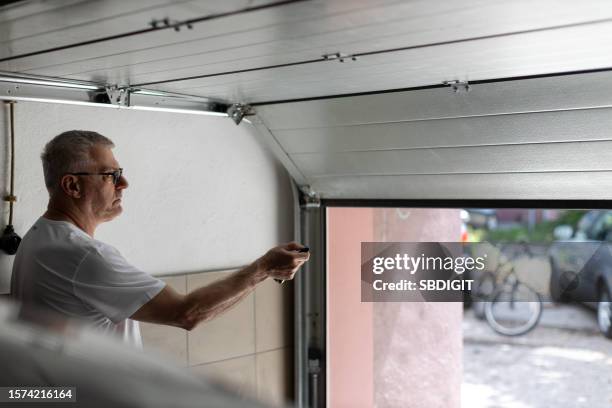 mature man closing garage door - door close button imagens e fotografias de stock