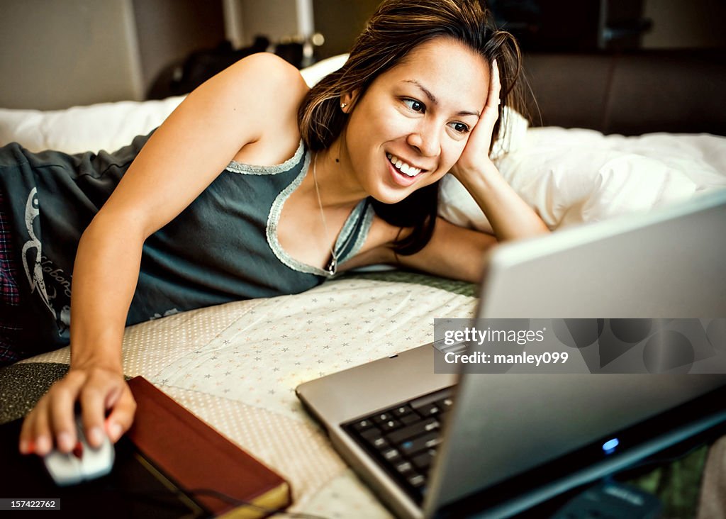 College student surfing the web on her bed