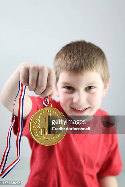 close up of 1 winner gold medal held by smiling boy - golden boy stock pictures, royalty-free photos & images