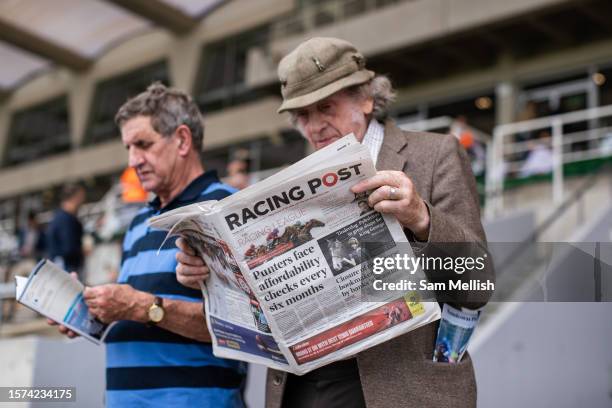 Racegoers read Racing Post newspaper during the Sandown races at Sandown Park on July 27, 2023 in Esher, England.