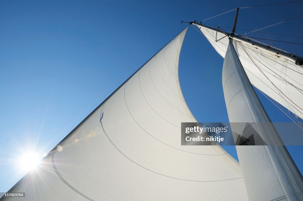 Sun shining from behind the sails of a yacht