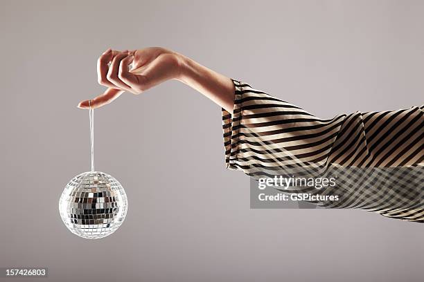 small disco ball dangling from woman's finger - silver disco ball stock pictures, royalty-free photos & images