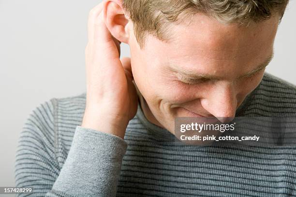portrait of a man scratching ear while looking away - shy stock pictures, royalty-free photos & images