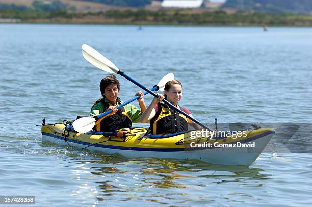 latino-américaine et caucasien adolescents kayak sur le corps de l'eau - girl rowing boat photos et images de collection