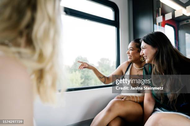 three young female friends riding the train together - zug fotografías e imágenes de stock