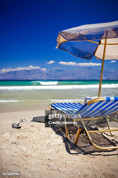 sun chairs and umbrella on beach - kreta stockfoto's en -beelden