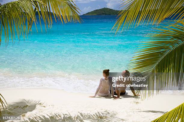 couple relaxing on the beach - tropische hitte stockfoto's en -beelden
