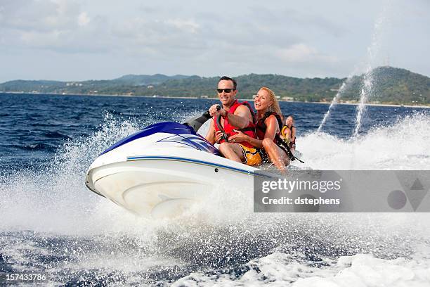 feliz pareja ridding motos acuáticas - jet boat fotografías e imágenes de stock