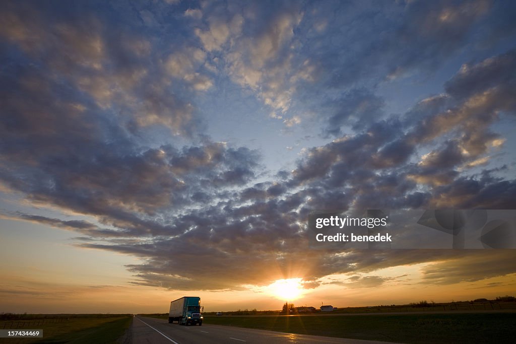 Truck passing by on highway during a glorious sunset