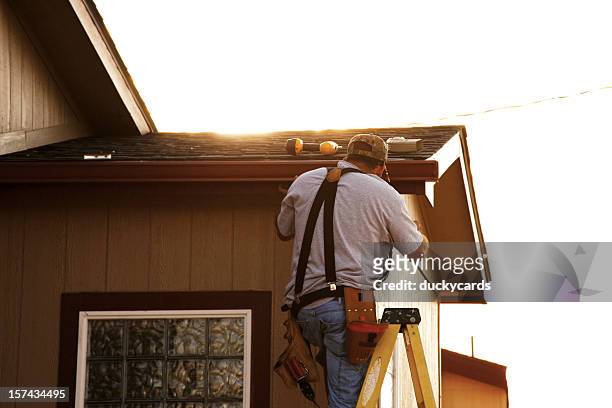 man installing seamless gutters - dakgoot stockfoto's en -beelden