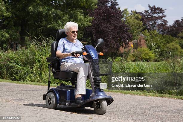 senior mujer montando un ciclomotor eléctrico - mobility scooter fotografías e imágenes de stock