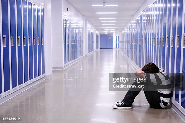 chico deprimido en el pasillo de la escuela - violencia escolar fotografías e imágenes de stock