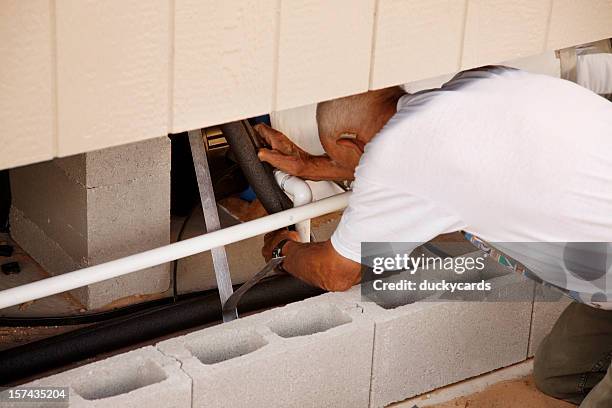 man insulating water pipes under home - house insulation not posing stock pictures, royalty-free photos & images