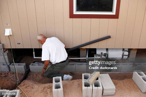 man insulating water pipes under home - house insulation not posing stockfoto's en -beelden