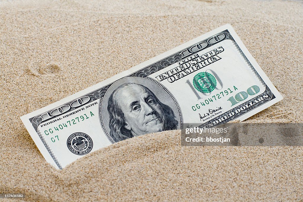 100 dollars sinking in the sand