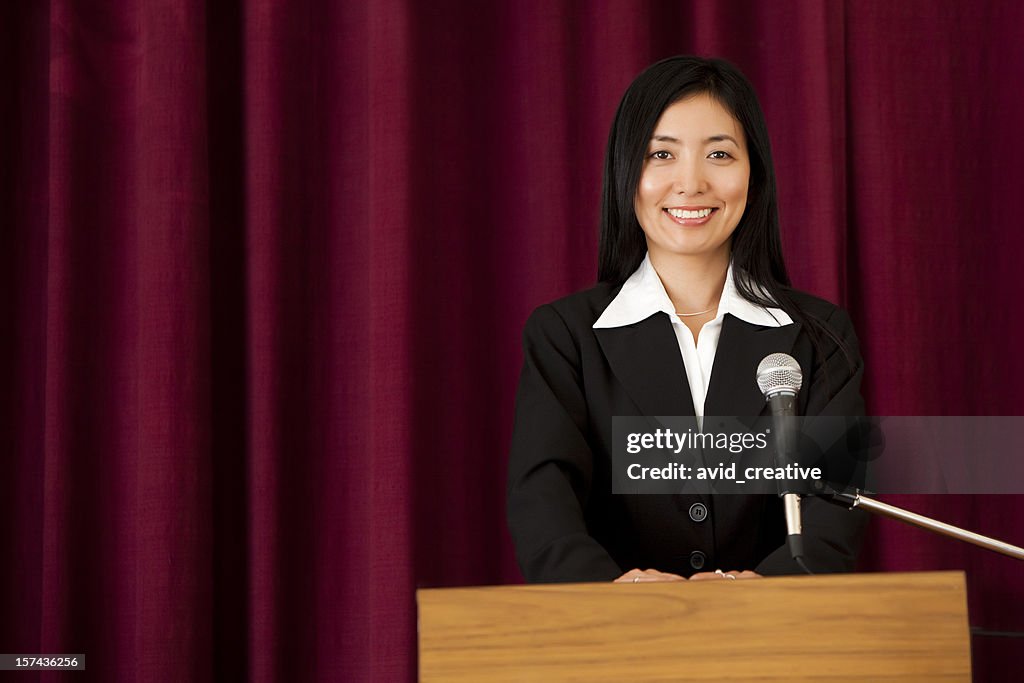 Smiling Asian Woman at Podium