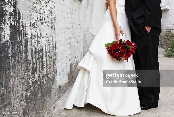 bride and groom in alley, red bouquet - black veil brides stock pictures, royalty-free photos & images