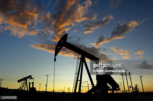 oil pumpjacks against a sunset sky - lost hills california stock pictures, royalty-free photos & images