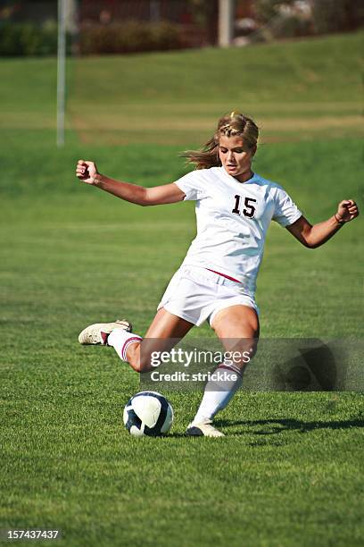 female soccer player in white power kicks with copyspace - girl kicking stock pictures, royalty-free photos & images