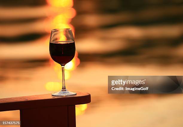 glass of red wine at sunset - adirondack chair closeup stock pictures, royalty-free photos & images