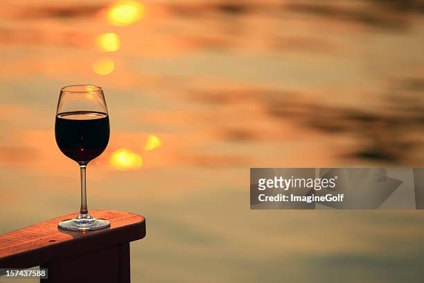 glass of red wine by the lake - adirondack chair closeup stock pictures, royalty-free photos & images