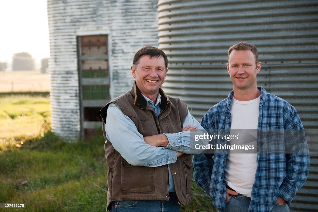 A father and son posing for a photo at a family farm