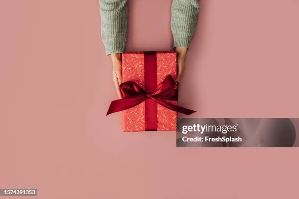 surprise d’anniversaire: un cadeau emballé dans un papier d’emballage rouge prêt à être livré - cadeau danniversaire photos et images de collection