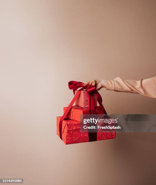 new year surprise: gifts wrapped in red and orange wrapping papers and tied with a big red ribbon ready to be delivered - blank packaging stockfoto's en -beelden