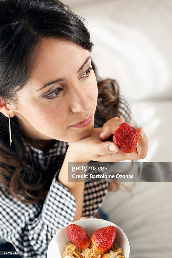 Thinkful beautiful young woman holding a fruit